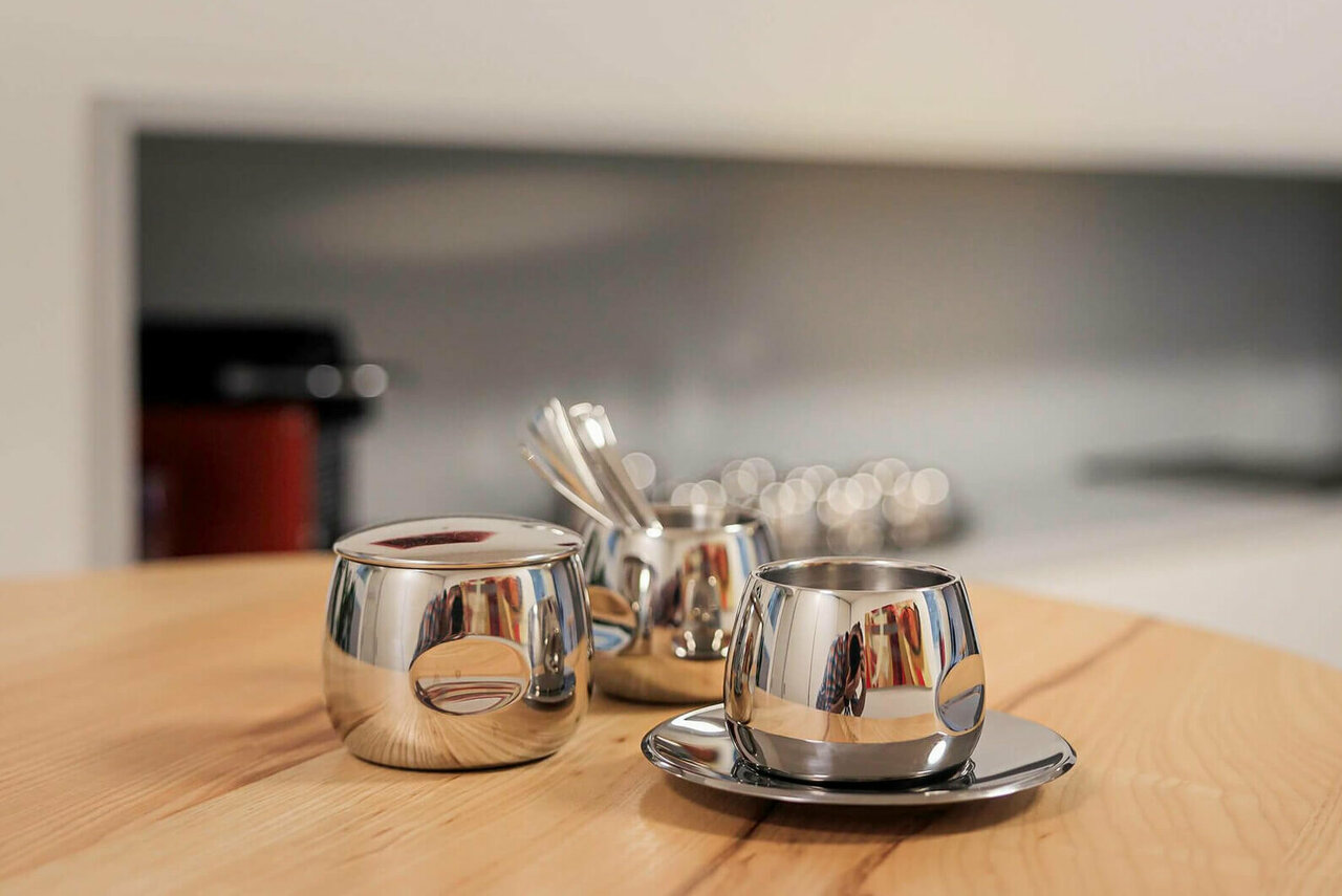 Silberne Kaffeetasse mit Löffeln auf einem Holztisch in der Küche