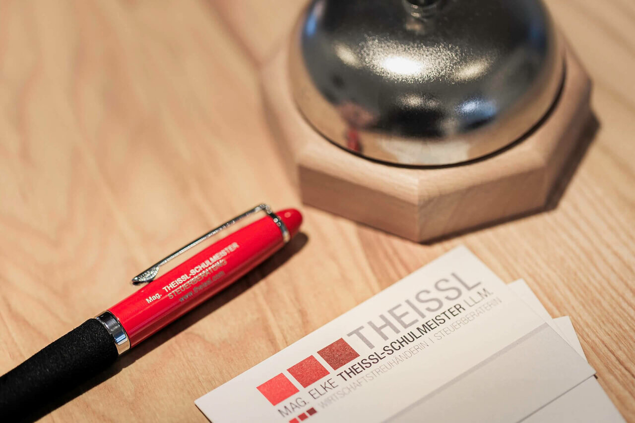 Theissl Visitenkarten mit einem roten Kugelschreiber neben einer Klingel