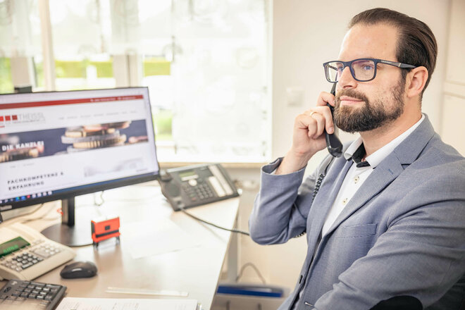 Mitarbeiter telefoniert vor seinem Computer